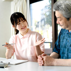 介護士が高齢者男性と会話をしている画像